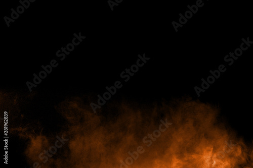Abstract orange powder explosion on black background. Freeze motion of orange dust particles splash.
