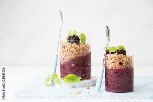 Glass of granola with berry yogurt on a light background. Copy space