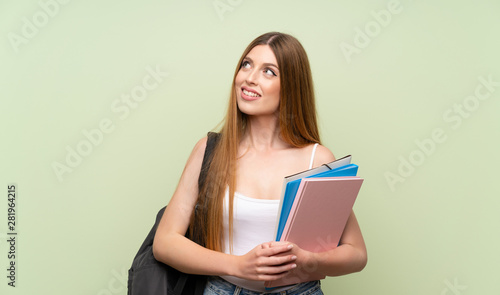 Young student woman over isolated green background laughing and looking up
