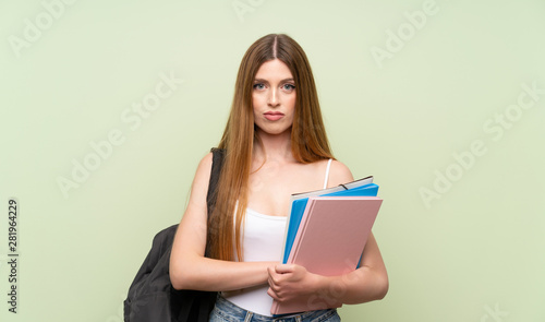 Young student woman over isolated green background keeping arms crossed