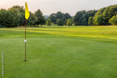 Putting Green mit gelber Fahne in der Abendsonne