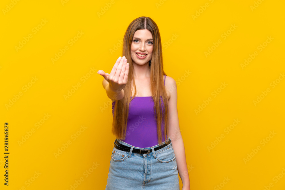 Young woman over isolated yellow background inviting to come with hand. Happy that you came Young woman over isolated yellow background inviting to come with hand. Happy that you came