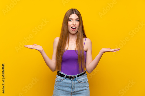 Young woman over isolated yellow background with shocked facial expression