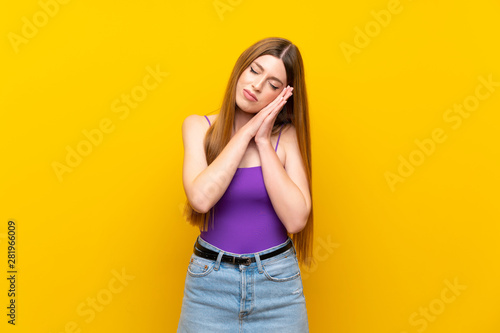 Young woman over isolated yellow background making sleep gesture in dorable expression