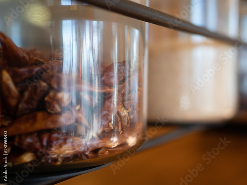 Dried red peppers in jar on display in bright storage room