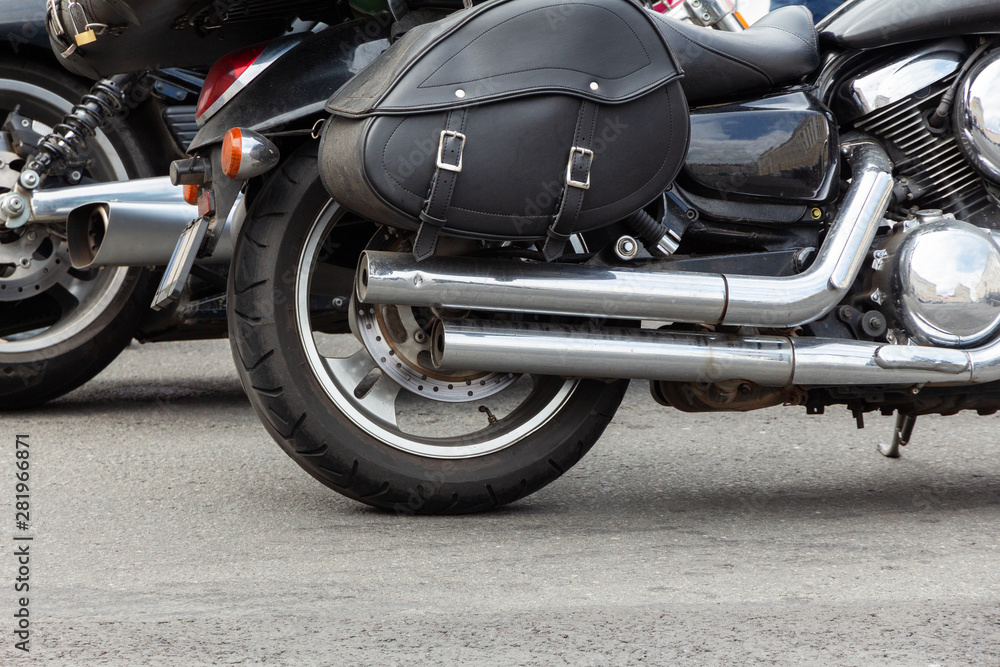 rear part of a motorcycle: wheel, exhaust pipe and black leather