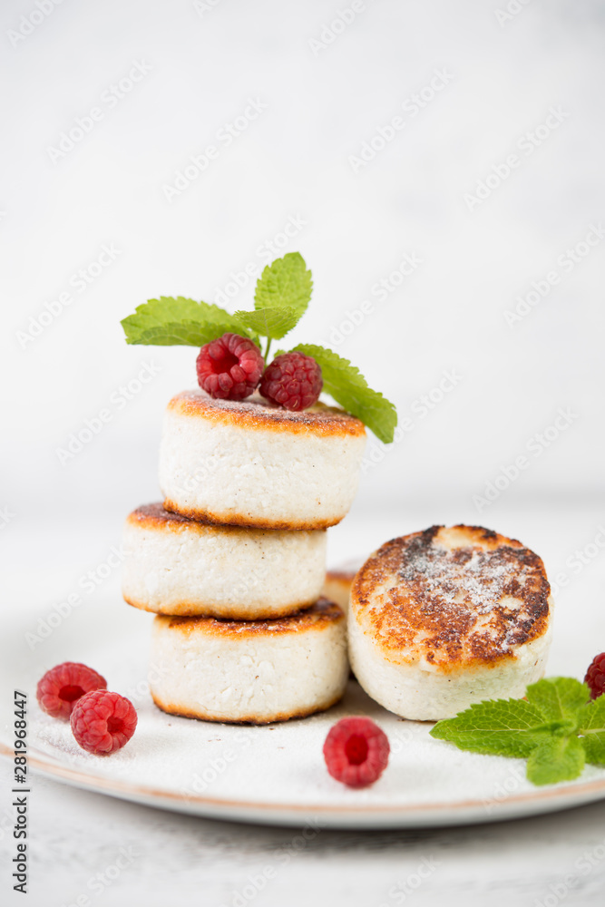 Fried curd cheesecakes decorated with fresh berries and mint. Vertical orientation.