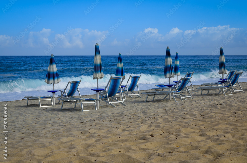 Liegestühle und Sonnenschirme in blau und weiß an einem Strand