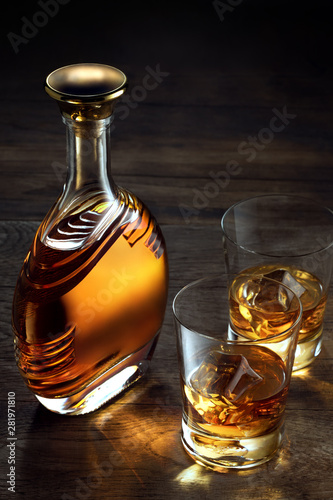 view of glasses of  whiskey and a bottle aside on color wooden  background. 