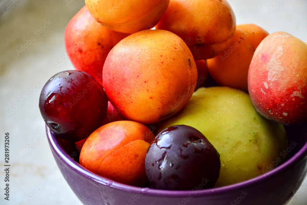 Juicy ripe fruits in a purple plate, which contrasts perfectly with the color scheme of apricots, peaches, apples and plums. An excellent charge of vitality and vitamins for the whole day.
