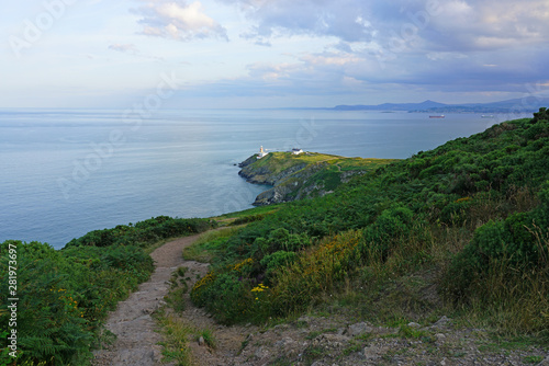 Photography View of green heather fields, the Baily Lighthouse and the Irish Sea seen from t