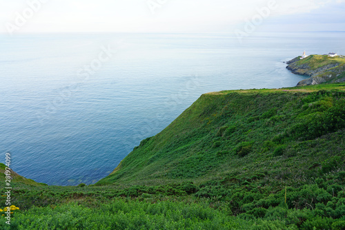 Photography View of green heather fields, the Baily Lighthouse and the Irish Sea seen from t