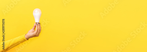 light bulb in hand over yellow background, panoramic mock up