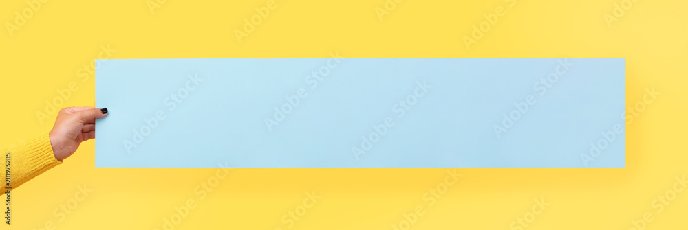 Mockup empty blank blue postcard holds the girl in her hand over yellow background, panoramic image Mockup empty blank blue postcard holds the girl in her hand over yellow background, panoramic image