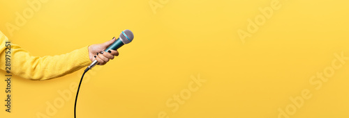 Obraz na płótnie hand holding microphone over yellow background, panoramic mock up image