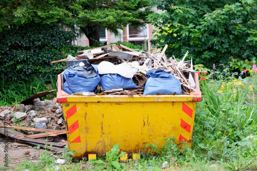 Yellow skip in countryside rural farmland for rubbish and waste 