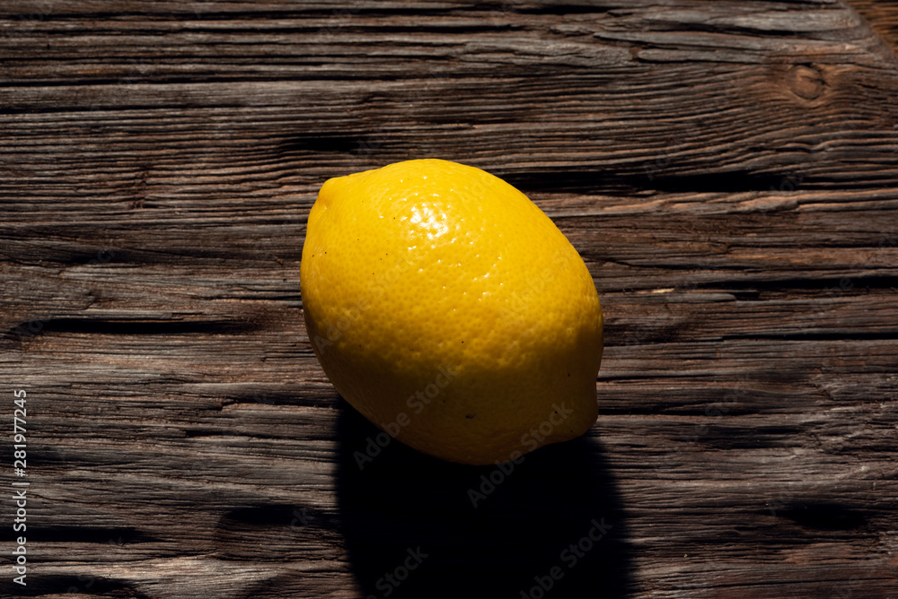 Fresh lemon on a brown wooden cutting board background.