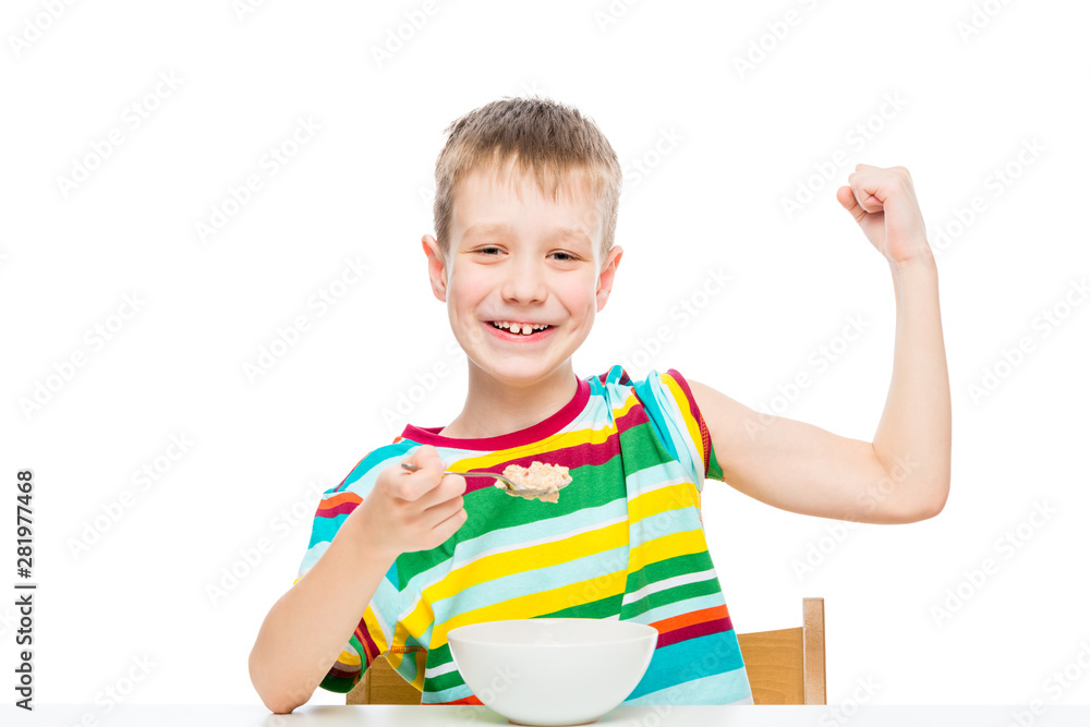 concept - proper nutrition, a strong healthy boy shows biceps, eats porridge concept - proper nutrition, a strong healthy boy shows biceps, eats porridge