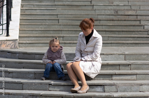 Child and mother sitting on stairs and waiting for somebody