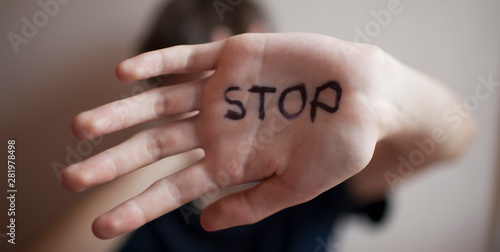 Teen boy protects himself with a palm with the word 