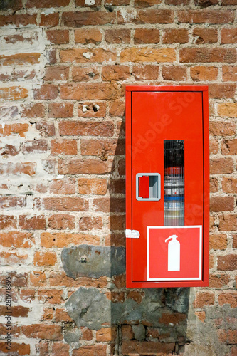 old red brick wall with red fire extinguisher box