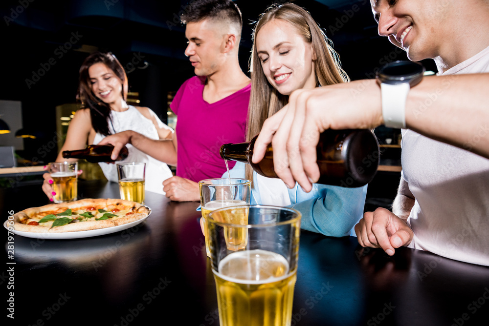 Cheerful friends in the pub. Drinking beer, wine and whisky, talking, having fun.