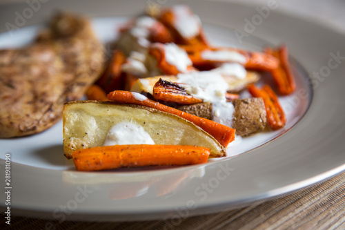 A simple, inexpensive meal: grilled chicken, roasted carrots and potatoes with a garlic sour cream sauce