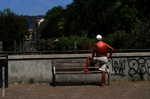Tanned man resting on a bench