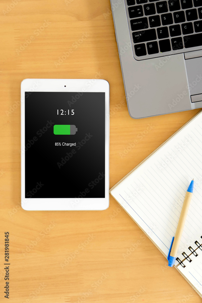 top view of business workspace to mobile phone with high charged battery screen, notebook and female hands typing on keyboard top view of business workspace to mobile phone with high charged battery screen, notebook and female hands typing on keyboard