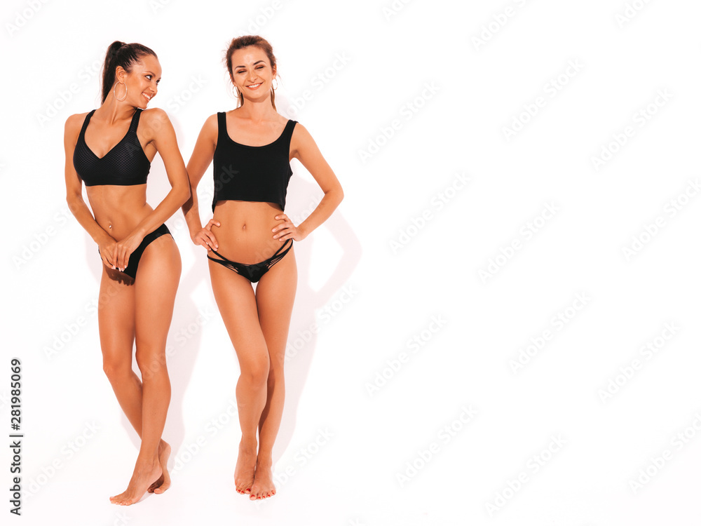 Two beautiful sexy smiling hipster women in black lingerie. Trendy hot  models having fun in studio. Girls isolated on white. Full length Stock  Photo | Adobe Stock