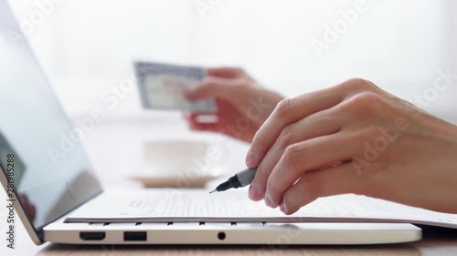 Woman freelancer with paper documents work on laptop at home-office. Blurred female hand hold social security number on background. Businesswoman fill out tax return form at work. Dolly shot