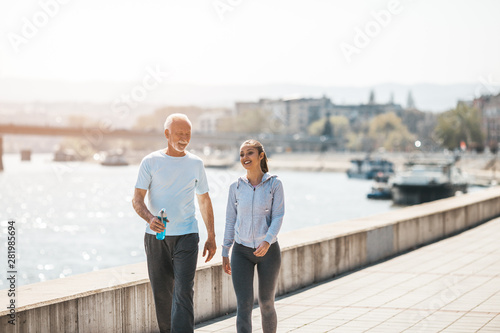 Fit senior man in good shape jogging and exercising together with his young adult daughter coach or instructor.