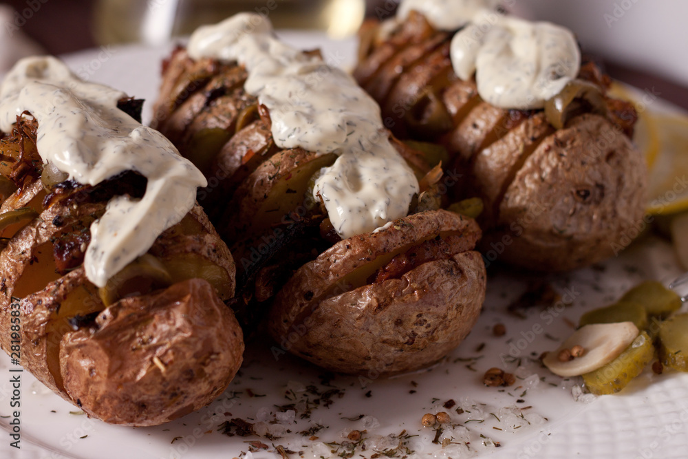 Baked potato with onions and spices on a white dish on the background of a wooden table Baked potato with onions and spices on a white dish on the background of a wooden table