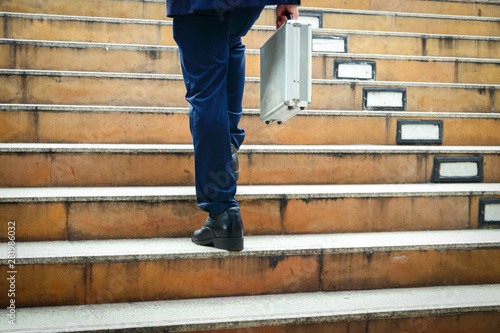 A businessman carrying a work bag is walking up the stairs to the office.