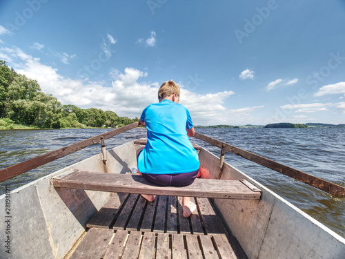 Young teenage boy rowing a rowboat or paddle boat on a lake
