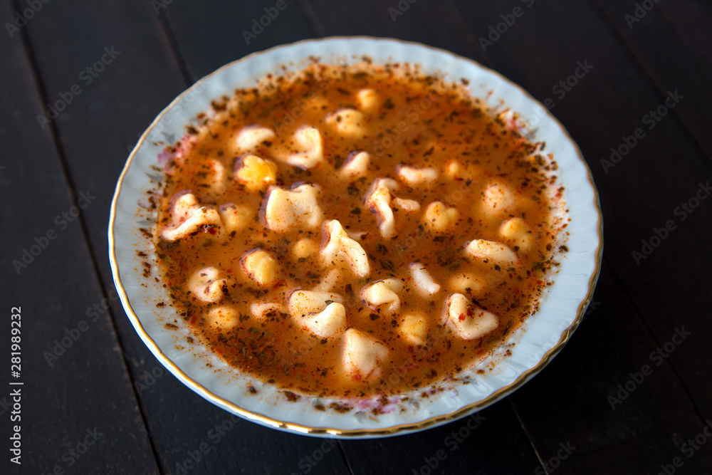 Turkish delicious traditional food Manti soup with tomato sauce, chickpea  and dry mint