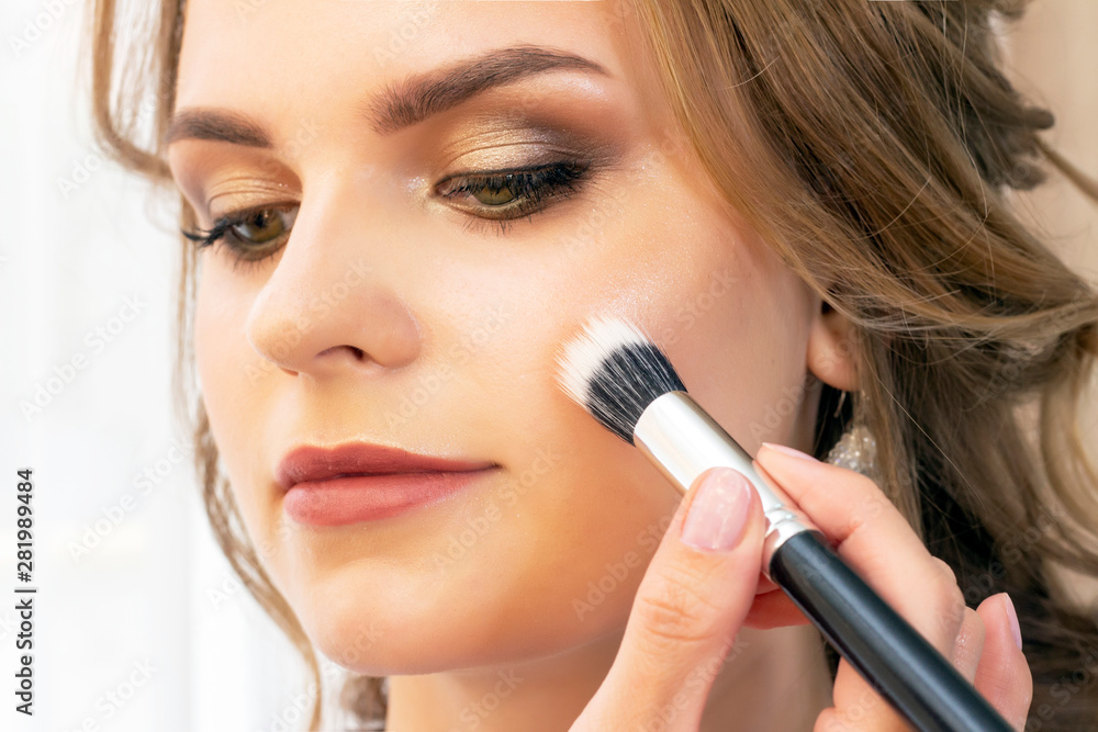 Makeup artist puts makeup on girl model. Brush powder on cheekbones and face. beautiful girl model, portrait. Nude colors in makeup. wedding, evening makeup. Makeup artist puts makeup on girl model. Brush powder on cheekbones and face. beautiful girl model, portrait. Nude colors in makeup. wedding, evening makeup.