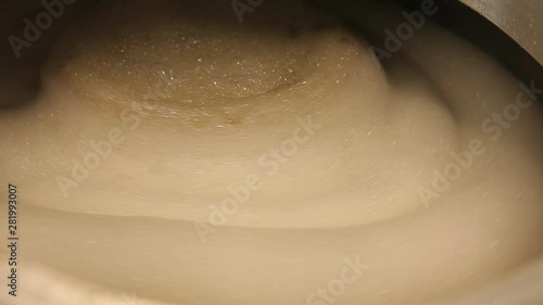 Beer is brewed and fermented in large aluminum tanks. Foam on the surface. Close-up.