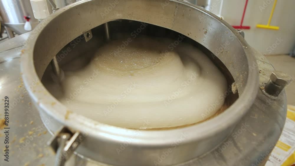 Beer is brewed and fermented in large aluminum tanks. Foam on the surface. Close-up. Beer is brewed and fermented in large aluminum tanks. Foam on the surface. Close-up.