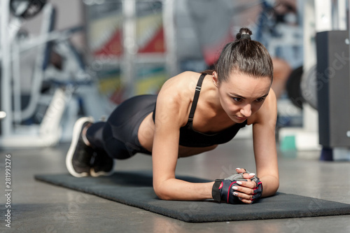 Young sporty woman doing plank exercise in a gym