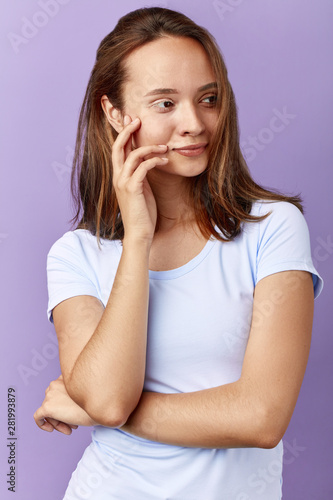 smiling awesome woman in white T-shirt touching her face, genetic predisposition . isolated blue background.