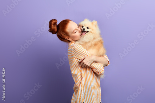 kind girl is embracing her dog as she hasn't seen it for a long time. girl has missed her pet. isolated blue background