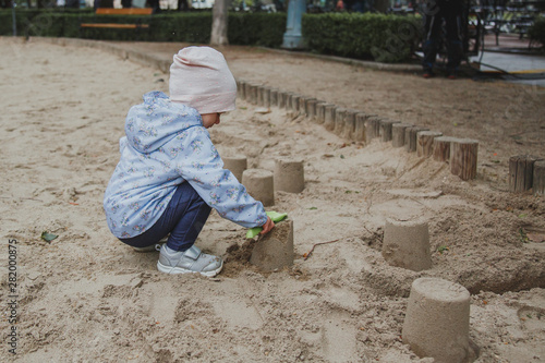 little cute girl builds sand cakes at a playground in the center of Budapest