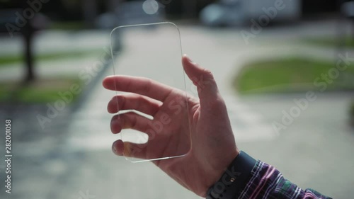 Future is now. Young excited man using furturistic mobile phone with transparent virtual touscreen for copy space animation. Outdoor view. photo