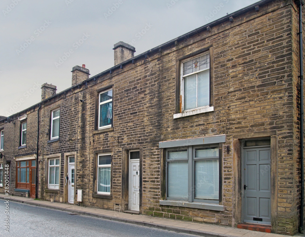 a row of traditional english old working class terraced houses on a street with grey cloudy sky