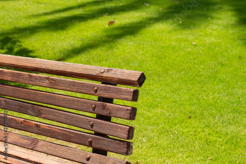 park outdoor landscaping infrastructure wooden bench object on unfocused green grass background in bright sunny weather time, copy space 