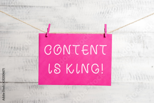 Word writing text Content Is King. Business photo showcasing marketing focused growing visibility non paid search results Clothesline clothespin rectangle shaped paper reminder white wood desk