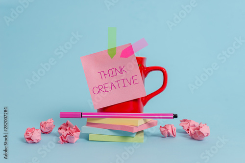 Writing note showing Think Creative. Business concept for The ability to perceive patterns that are not obvious Coffee cup pen note banners stacked pads paper balls pastel background