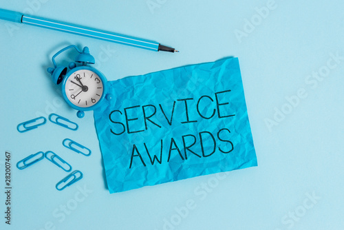 Word writing text Service Awards. Business photo showcasing Recognizing an employee for his or her longevity or tenure Metal alarm clock blank crushed sheet marker clips sky colored background
