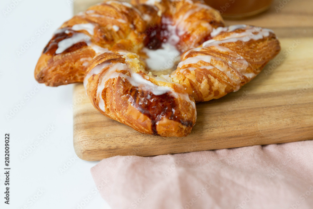 Close up of Strawberry and Sweet Cheese Danish with Icing Drizzle on Wooden Serving Board, Pink Napkin, Fruit Pastry Flat Lay on White Background